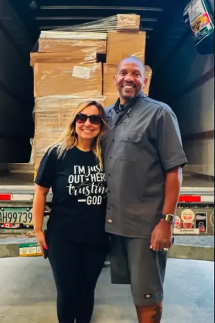 Ida with a volunteer in front of a truck loaded with pallets of donated food