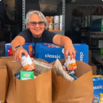 A volunteer holding up bags of groceries