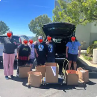 Volunteers handing out groceries from the back of a car