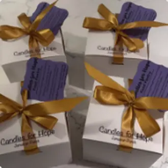Finished candles boxed and tied with gold and purple ribbon